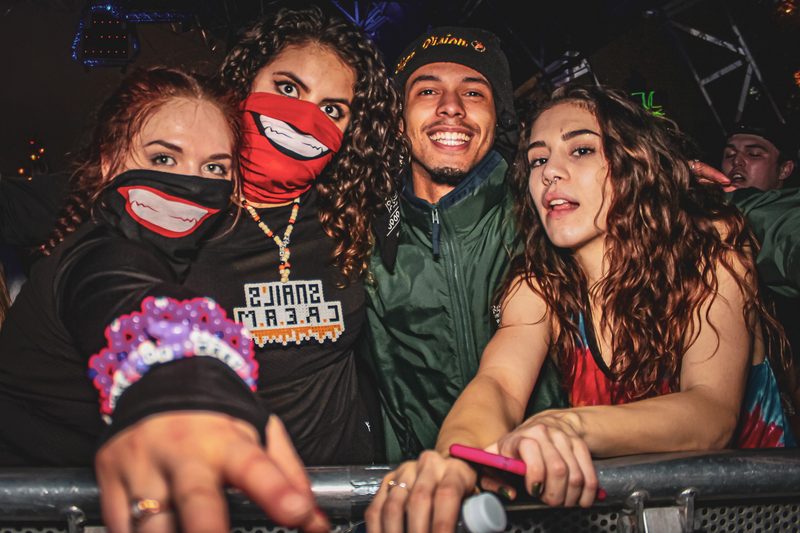 A group at the front rail of a live event, several wearing branded apparel