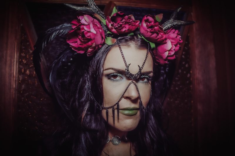 Editorial portrait of a model wearing a handmade chain headpiece and floral crown