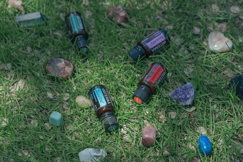 Overhead flat lay of essential oil bottles and polished crystals arranged on grass
