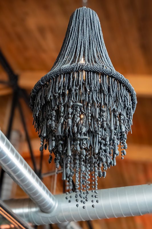 A beaded fringe chandelier hanging against warm wood ceiling beams