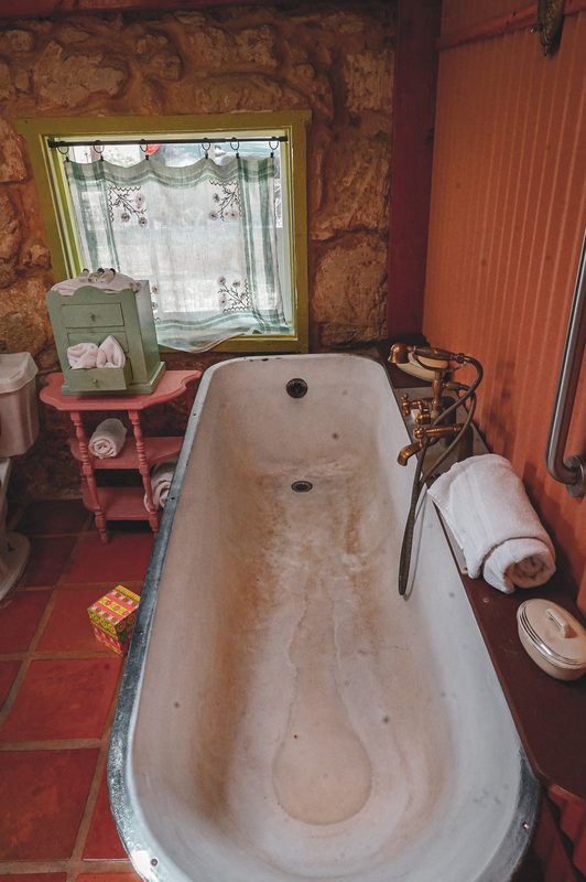 A clawfoot tub against a terracotta wall in a rustic lodge bathroom