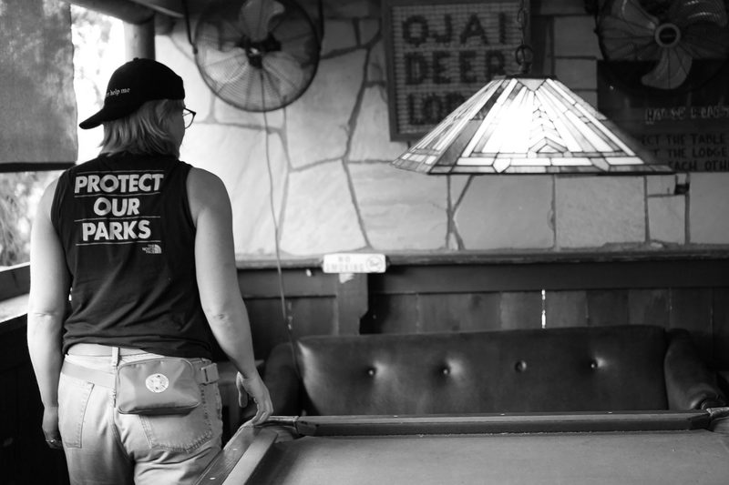 Black and white interior of a lodge bar room with a figure standing at the counter
