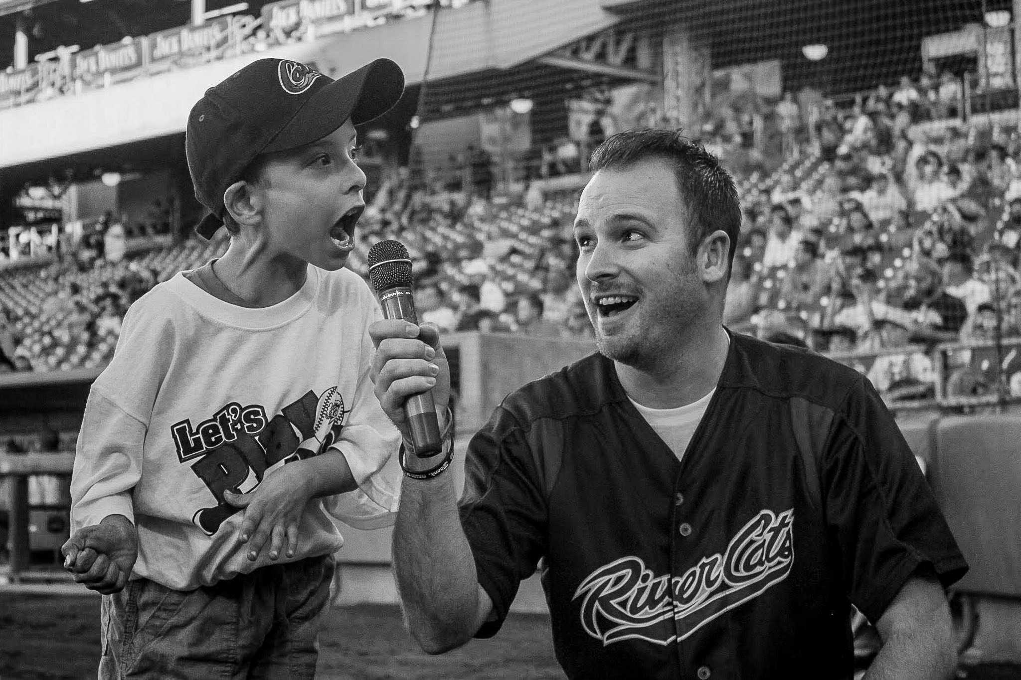 Documentary brand photography at a live sports event with a child singing on the stadium field