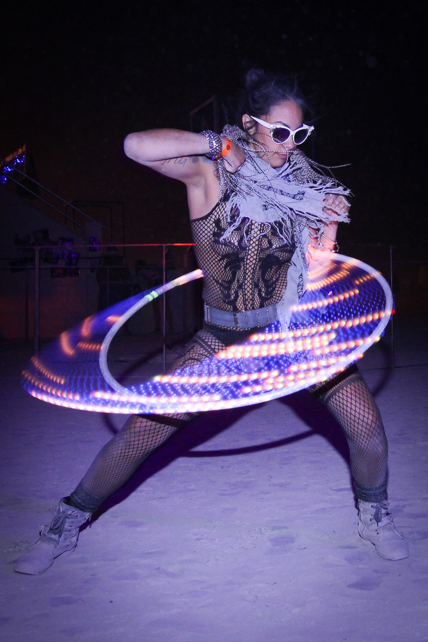 Performer creating circular light trails with an LED hula hoop in a long-exposure photograph