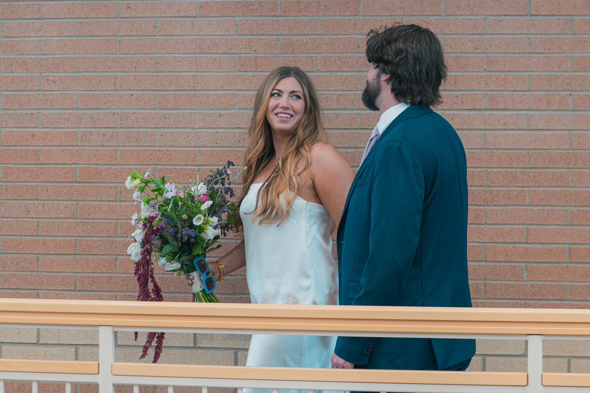 Bride laughing with her groom at the courthouse terrace railing during their Denver elopement