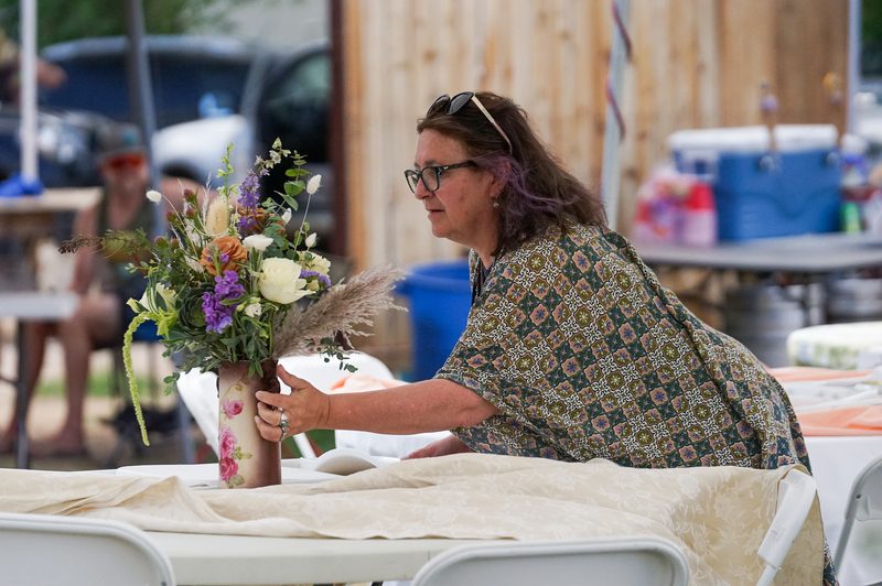 Woman arranging a colorful bouquet on a table before an outdoor wedding in California