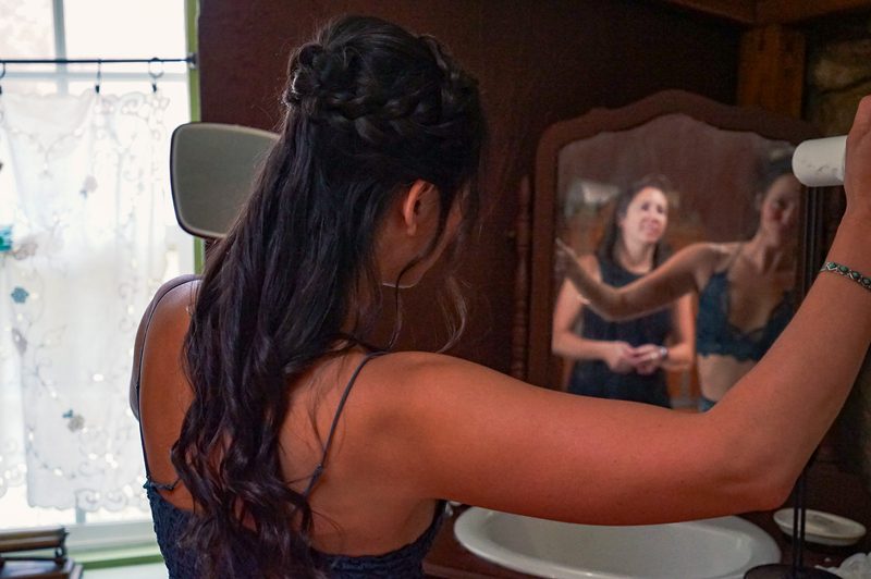 Bride with an intricate braided hairstyle and her mirror reflection while getting ready