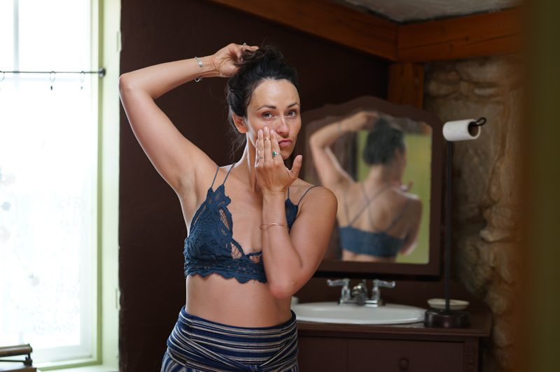 Bride fixing her hair at a mirror while getting ready for her hot spring wedding