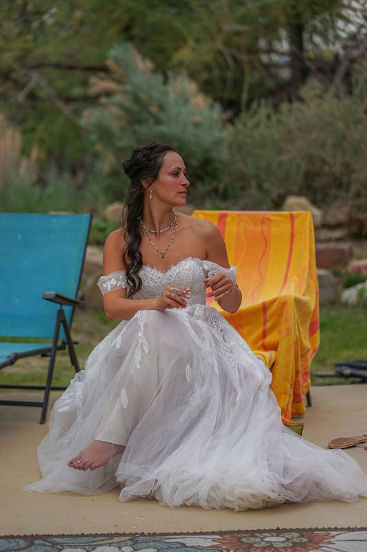Bride in her flowing wedding gown seated near an orange towel and blue chair at a hot spring venue