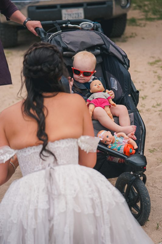 Bride seen from behind beside a baby in a stroller at a hot spring wedding