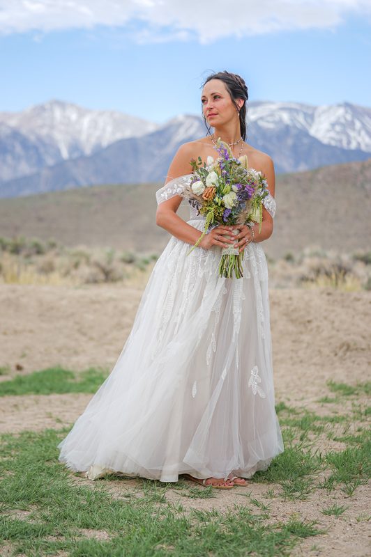 Bride holding a wildflower bouquet in front of snow-capped mountains at a California elopement and intimate wedding