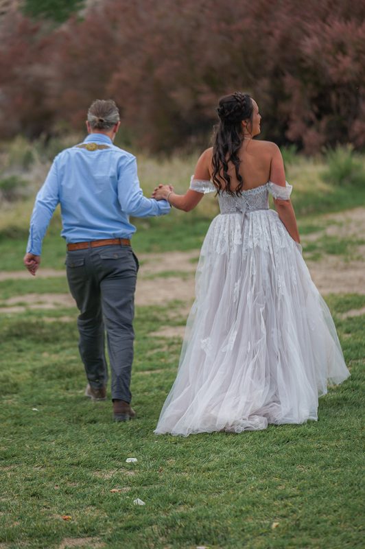 Bride and groom walking hand in hand across a grassy field after their ceremony