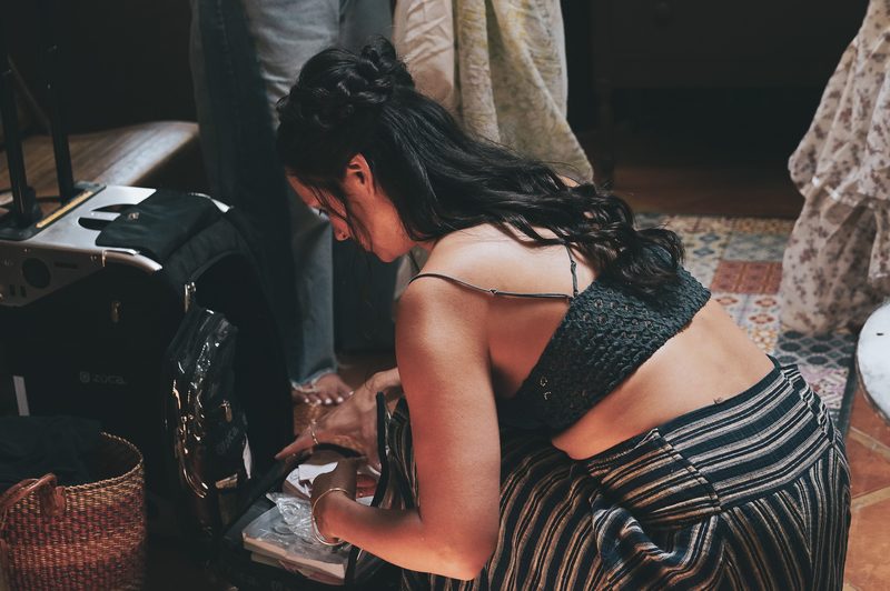 Woman getting ready on the wedding day, adjusting jewelry beside her bag