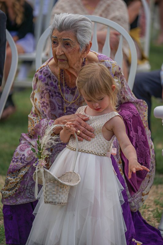 Close moment between a grandmother and a flower girl at an outdoor wedding ceremony