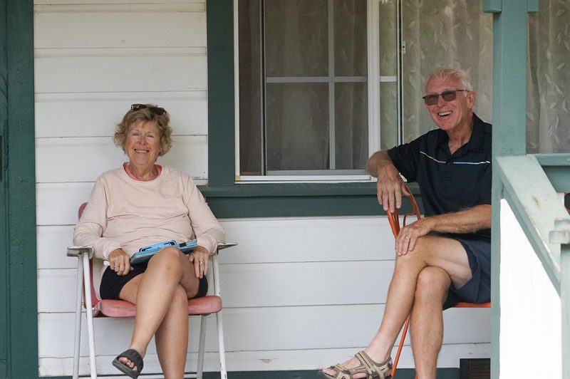 Older couple smiling together on a farmhouse porch during a wedding weekend
