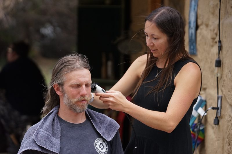 Woman helping a groom with grooming while he gets ready for his wedding
