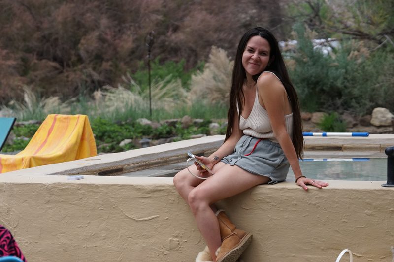 Smiling woman sitting on the edge of a stone hot spring tub at a wedding weekend