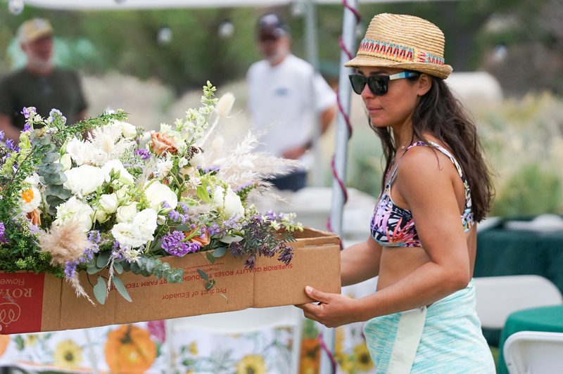 Woman in a sun hat carrying a box of wedding bouquets at a hot spring wedding