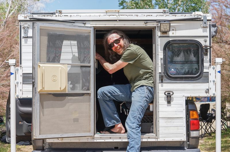 Man in sunglasses stepping out of a camper door during a hot spring wedding weekend