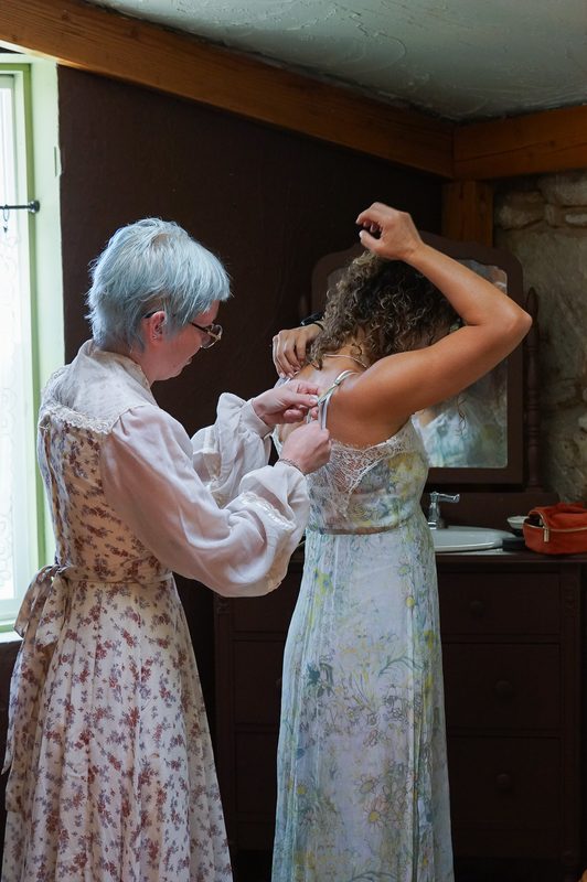 Older woman helping another woman with her dress before a hot spring wedding