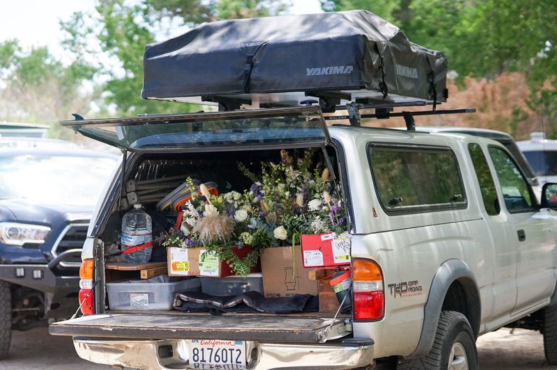 Truck bed loaded with fresh wedding flowers and a rooftop tent before a hot spring wedding