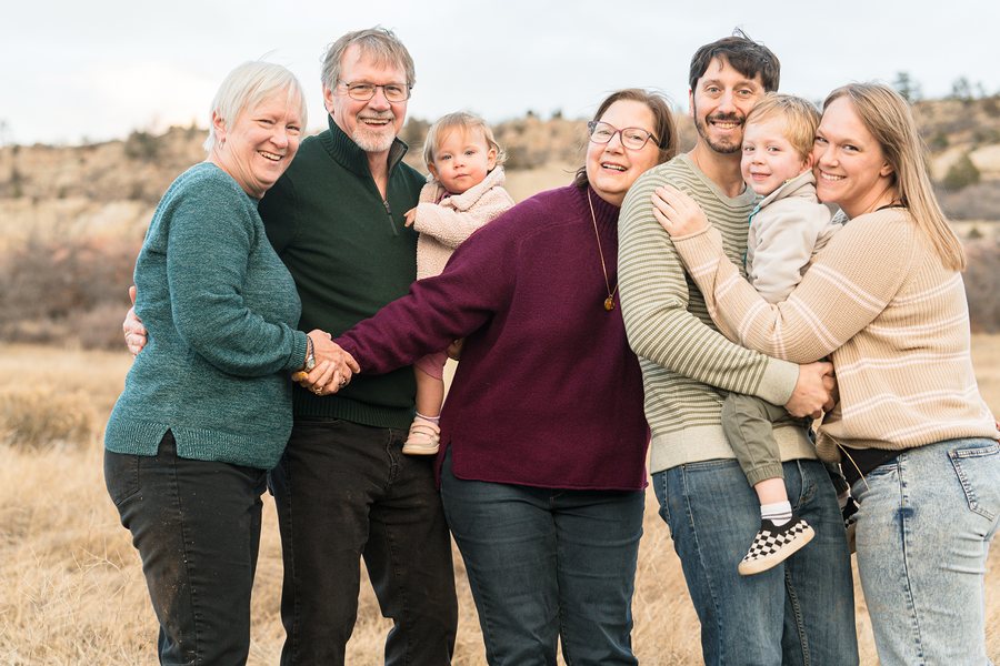 An extended family of three generations hugging and laughing together in a golden autumn field