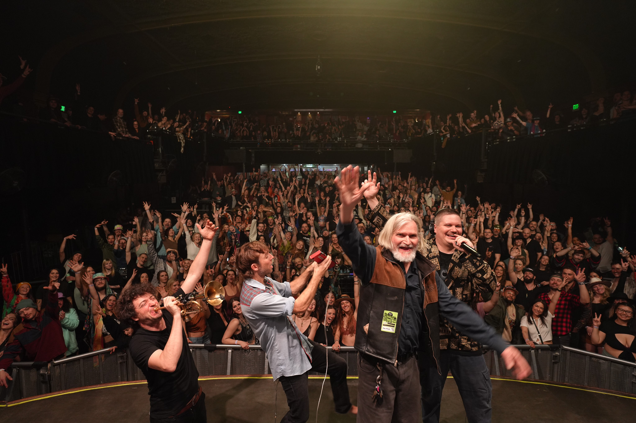 Full band performing on stage to a packed venue crowd during a live music tour