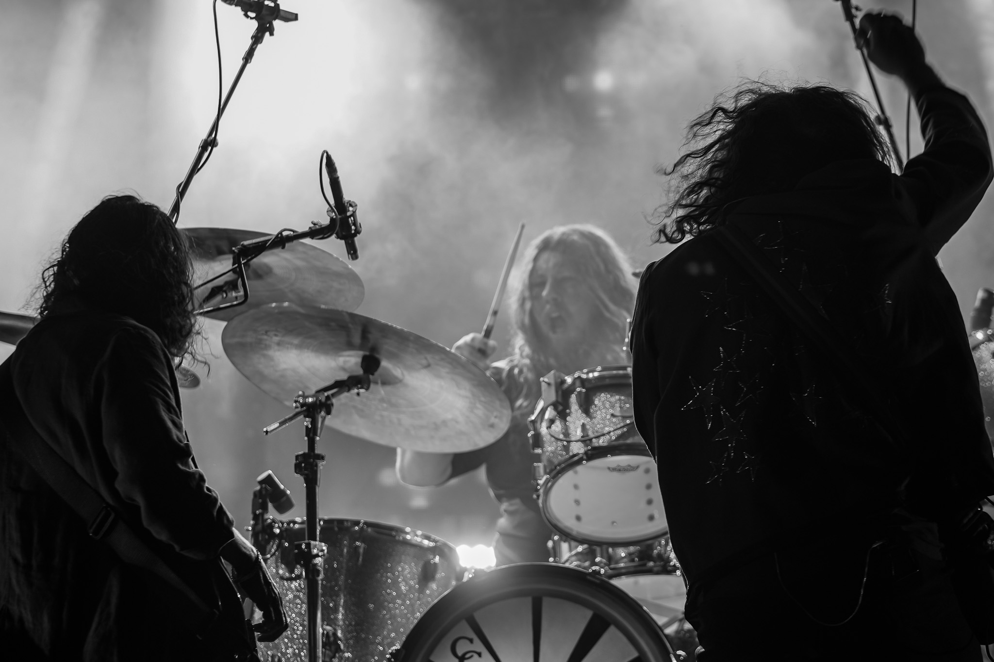 Three-person stage scene with atmospheric smoke at a live concert