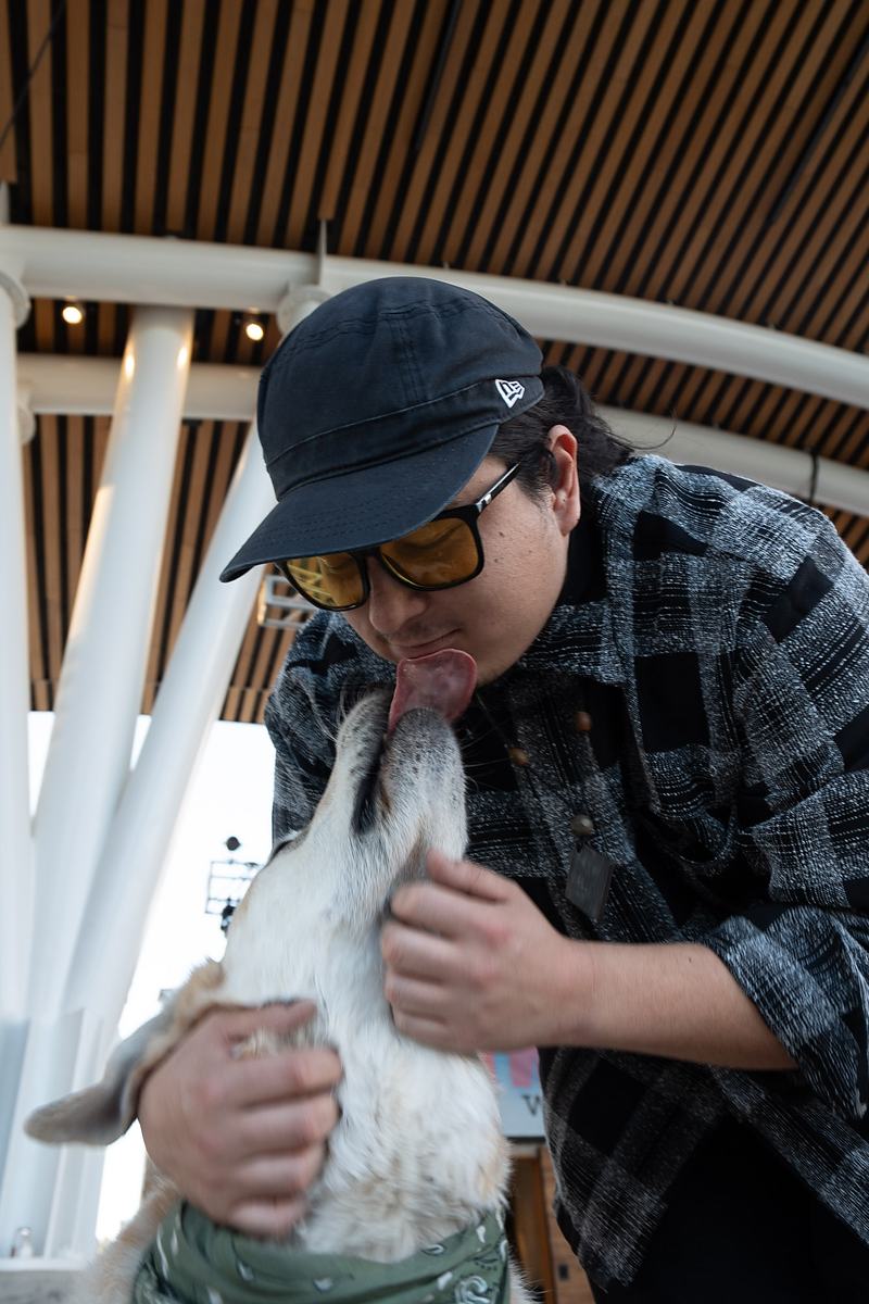 A band member cradles the tour dog in the shade of the amphitheater before the Winter Park performance, behind-the-scenes tour documentary photography