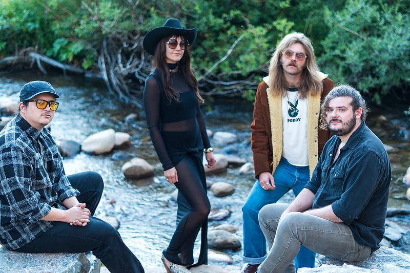 The members of Rainy Eyes gather for a riverside band portrait among the rocks of a Winter Park creek