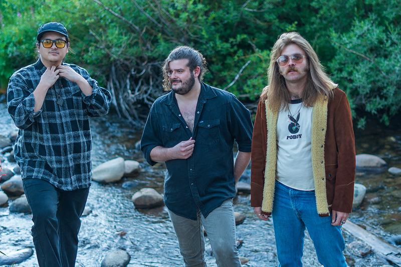 The band moves through a shallow mountain creek during a riverside portrait session in Winter Park