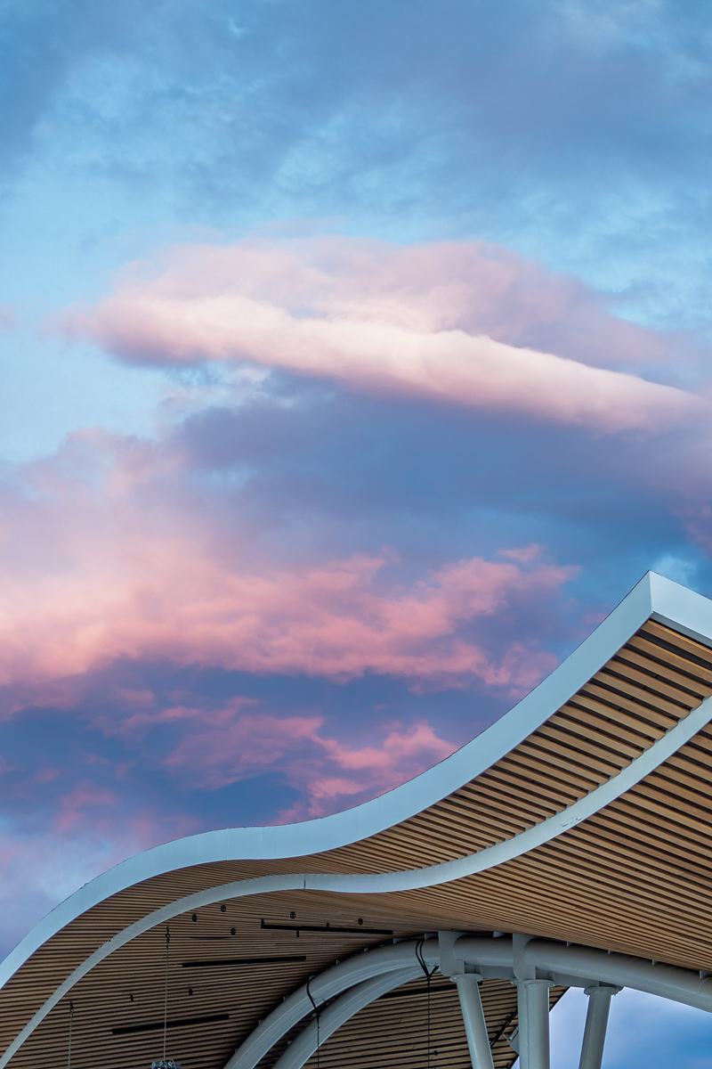 Pink dusk clouds break over the curved wooden roof of the Rendezvous Event Center amphitheater after the rain