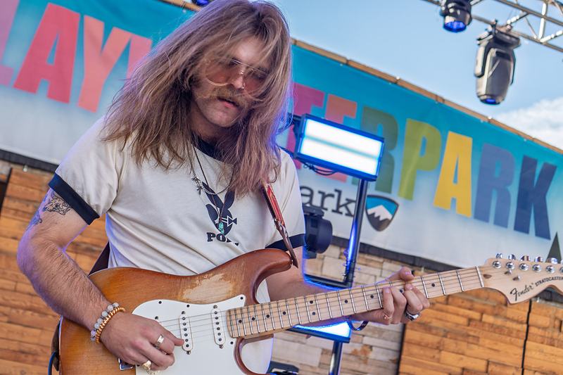 A Rainy Eyes guitarist plays a solo on electric guitar in front of the Play Winter Park backdrop, Winter Park concert photographer Tara Lenehan