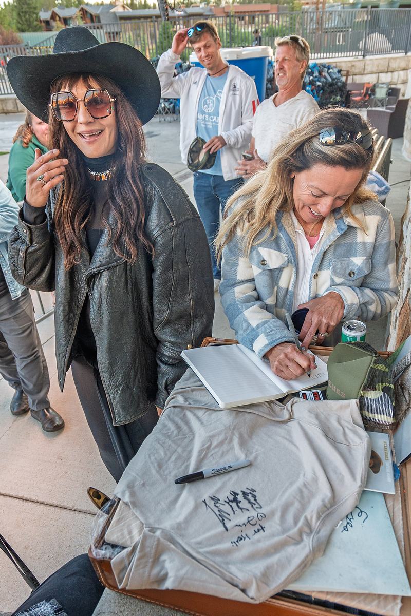 The vocalist and a bandmate hand over merchandise and tote bags at the merch table in Winter Park