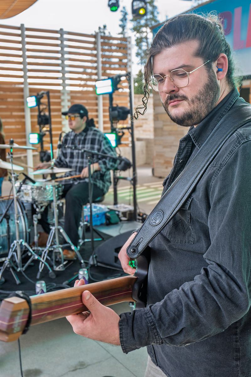 A Rainy Eyes musician plays a stringed instrument in profile on stage