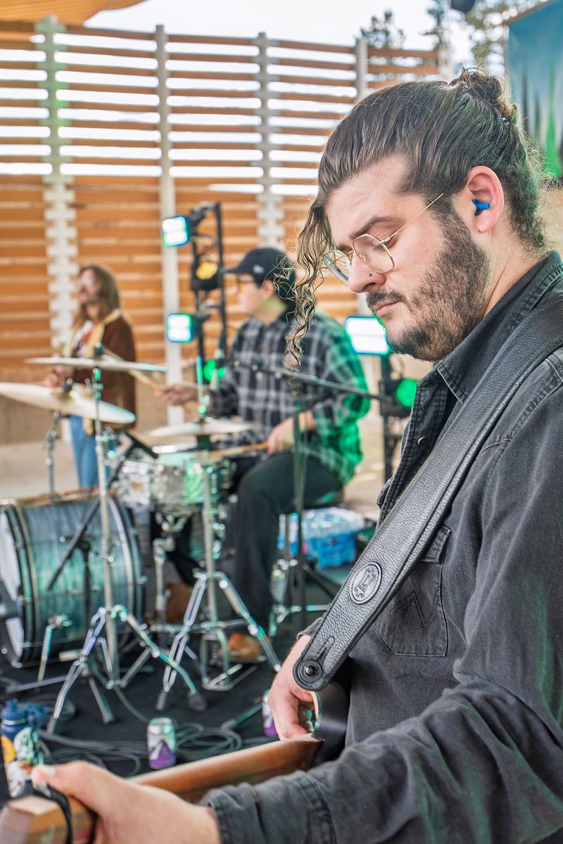 A Rainy Eyes musician looks down in concentration while playing on stage, Winter Park concert photography