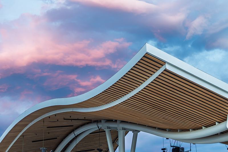 Sunset colors the sky above the curved wooden roofline of the Rendezvous Event Center