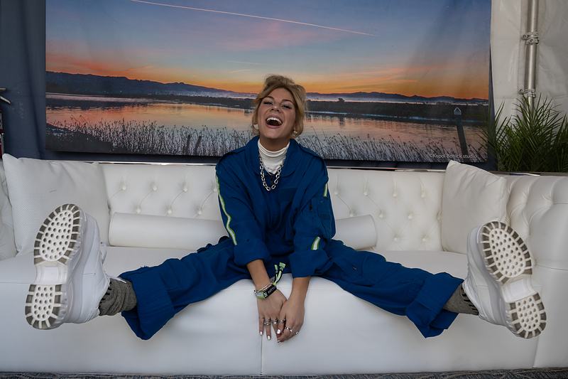 Backstage lounge — person in a blue jumpsuit, festival environment photography