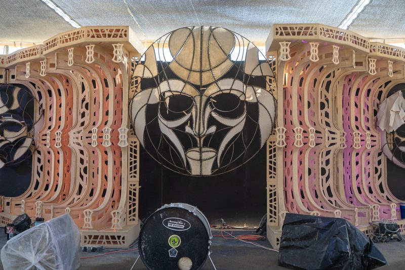 Ornate carved wooden facade with a large black and white face at Burning Man