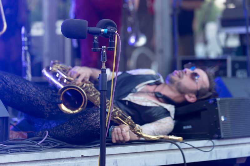 Saxophonist lying back on a stage beside a microphone with his saxophone at Burning Man