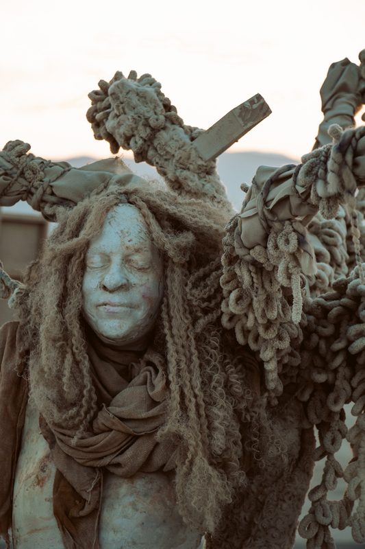 Weathered sculpture of a face with branch-like details at Burning Man