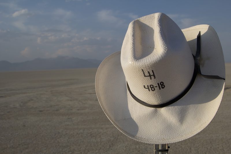 White cowboy hat on a post against a wide desert horizon at Burning Man
