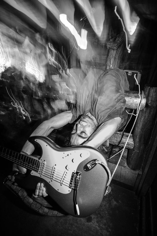 Black and white photo of a guitarist bending backward with motion blur during an Insects vs. Robots show