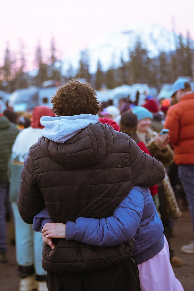 Two people in winter coats embrace in the crowd at the RendezVan 2026 festival in Bend