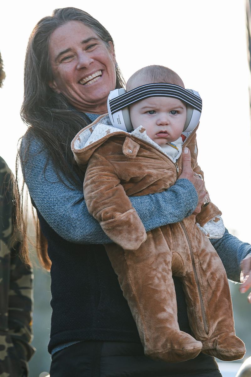 An adult holds a small child in a bear costume at an outdoor winter music festival in Bend