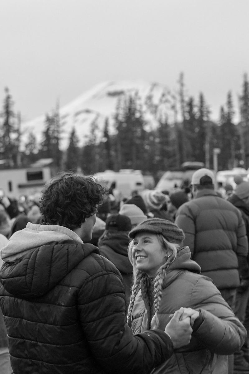 Black and white photograph of a winter festival crowd with a snowy backdrop at RendezVan 2026 in Bend