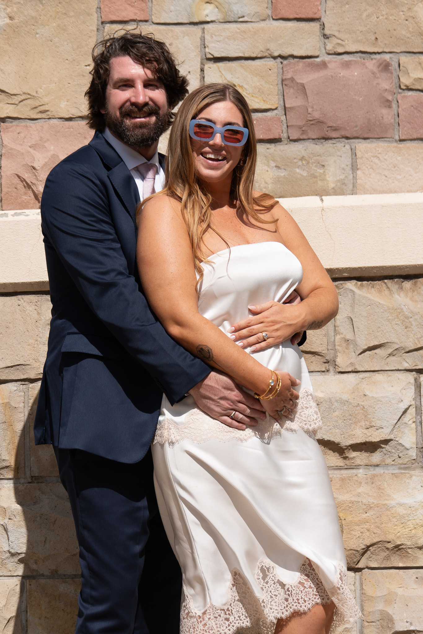 Laughing couple in wedding attire posed outside the courthouse after their elopement